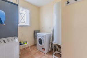 a laundry room with a washing machine and a window at Le Pin Franc in Valeyrac