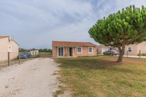 a house with a tree in front of a yard at Le Pin Franc in Valeyrac