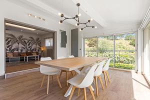 a dining room with a wooden table and white chairs at Villa Palmier avec piscine in Roquebrune-sur-Argens