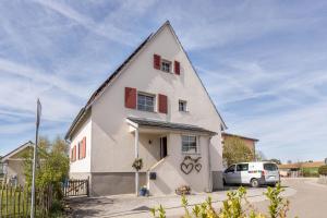 a white house with a car parked in front at Behagliche Wohnung Hüfingen in Hüfingen