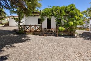 a white house with a tree and a brick driveway at Quinta O Refúgio in Azambuja
