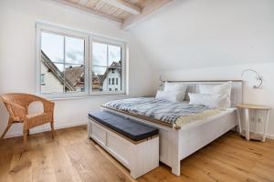 a white bedroom with a bed and a window at Maison Mer Baltique in Dranske