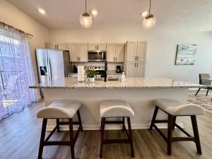a kitchen with a large island with two bar stools at The Meadowlark at Coventry Rows in Omaha
