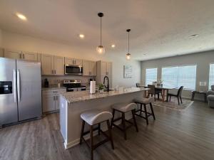 a kitchen with a refrigerator and a table with chairs at The Meadowlark at Coventry Rows in Omaha