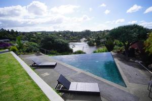 a swimming pool with two chairs and a river at Riverview Retreat in Kerikeri