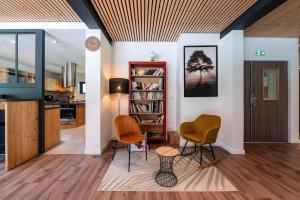 a living room with two chairs and a book shelf at Hostel du Val de Tamié in Faverges