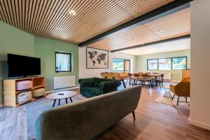a living room with a couch and a tv at Hostel du Val de Tamié in Faverges