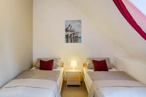two twin beds in a attic room with red pillows at Gulfhof Oldersum Dachgeschoss in Moormerland