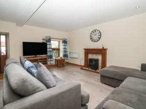 a living room with a couch and a clock on the wall at Mulberry Manor in Hull
