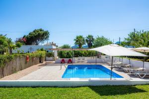 a swimming pool with an umbrella and lounge chairs and a swimming pool at Finca Blanca in Calas de Mallorca