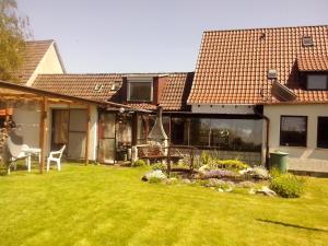 a backyard of a house with a lawn and a house at Ferienwohnung Hiddenseeblick 1 in Dranske