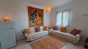 a living room with two white couches and a painting at Syros Mandala Studios in Megas Gialos - Nites