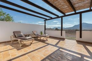 a patio with two chairs and a table with mountains in the background at Casa Tagaide in Tuineje