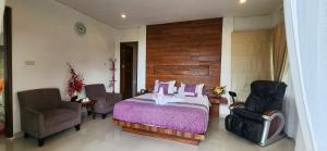a bedroom with a bed with a purple blanket and two chairs at Grace Hill Villa Lubuk Minturun in Padang +59 photos