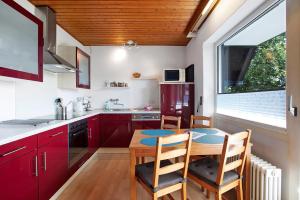 a kitchen with red cabinets and a wooden table and chairs at Haus vor Anker in Feldberg