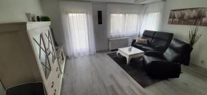 a living room with a black couch and a table at Ferienwohnung Küssaberg in Küssaberg