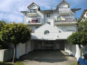 a large white building with balconies and a parking lot at Ferienwohnung Küssaberg in Küssaberg