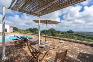 a patio with a table and chairs and an umbrella at Alto da Lua - Aljezur in Bordeira