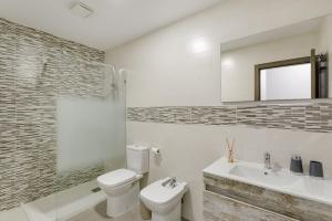 a bathroom with a toilet and a sink and a mirror at Edificio Bentejui 2 in Las Palmas de Gran Canaria