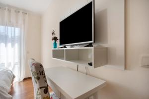 a white living room with a tv on a wall at T0 Grota in Buarcos