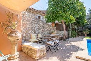 a patio with a table and chairs next to a wall at Ca'n Blanch in Biniamar