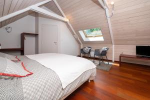 a bedroom with a bed and two chairs and a television at Longère de Nivinen in Arzano