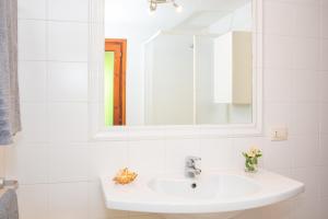 a white bathroom with a sink and a mirror at Appartamento del Cormorano in Olbia +17 photos