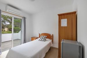 a bedroom with a bed and a tv and a window at Pensión las 3 Golondrinas in Santa Eularia des Riu