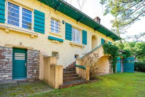 a house with blue shuttered windows and stairs at Villa Eole - plein centre Hossegor in Soorts-Hossegor