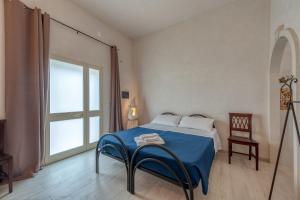 a bedroom with a bed with a blue blanket and a window at Anghelos in Lizzanello