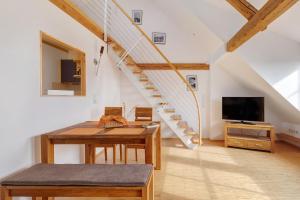 a living room with a table and a tv and stairs at Birkethof Romantik-Appartement in Mickhausen