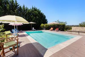 a swimming pool with two umbrellas and chairs at Quinta O Refúgio in Azambuja