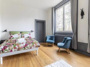 a bedroom with a bed and two blue chairs at Château De Saint Mayeul in Joze