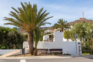a white building with a bench and palm trees at Maracas 2 in El Pozo de los Frailes