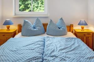 a bedroom with a bed with blue pillows and a window at Haus Seeadler Wohnung 11 in Koserow
