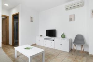 a white living room with a tv and a table at Apartamento Perez Zara 3 in Conil de la Frontera