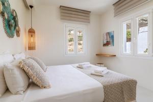a white bedroom with a bed with two windows at Aeolos Villa Erato in Agkidia +18 photos