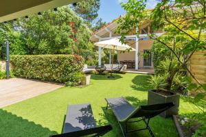 a garden with chairs and an umbrella and grass at Dune Lodge 2- Capbreton Hossegor - in Capbreton