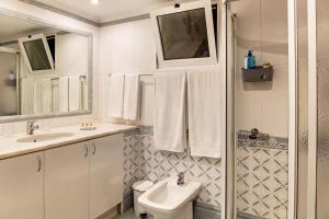 a white bathroom with a sink and a toilet at Villa Echium T1 in Caniço