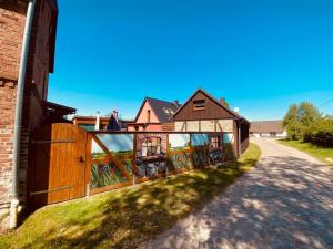 a house with a wooden fence next to a road at Alte Schmiede in Melzow