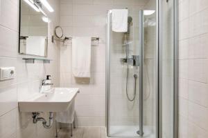 a white bathroom with a shower and a sink at Appartement Mia in Ihrlerstein +15 photos