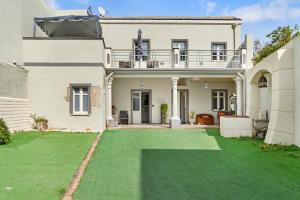a large white house with a green lawn at Luxar Suites and Apartments in Assemini