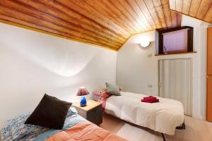 a bedroom with two beds and a wooden ceiling at Casa del sole in Toceno