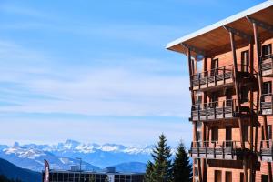 a building with balconies and mountains in the background at Les Airelles in Chamrousse +17 photos