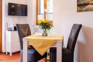 a vase of flowers on a table with two chairs at Gästehaus Wolfgang Weitsee in Ruhpolding