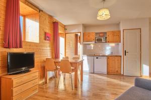a kitchen and dining room with a table and a television at Les Airelles in Chamrousse