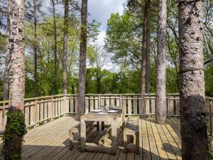 a wooden deck with a picnic table and trees at La Cafoutche Tiny in Gommenecʼh