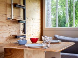 a wooden table with plates and wine glasses on it at La Cafoutche Tiny in Gommenecʼh +16 photos