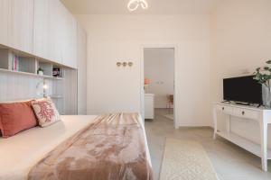 a white bedroom with a large bed and a tv at La Casa dei sognatori in Villasimius