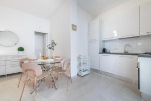 a kitchen with white cabinets and a table and chairs at La Casa dei sognatori in Villasimius